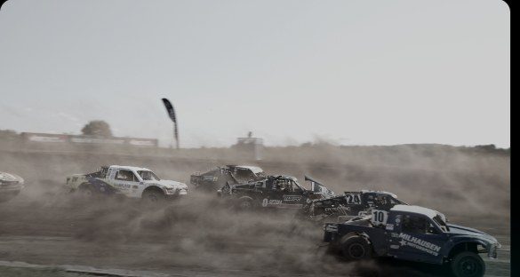 Short-course trucks racing through dust