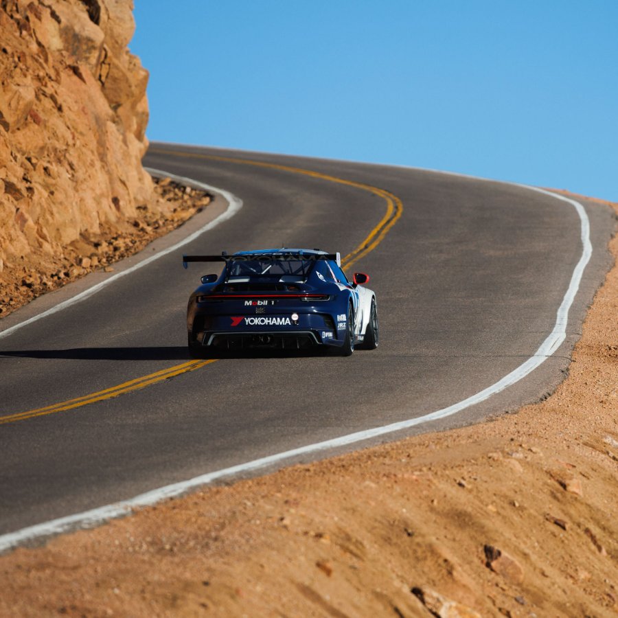 Blue race car heading up a rocky switchback above the tree line at Pikes Peak